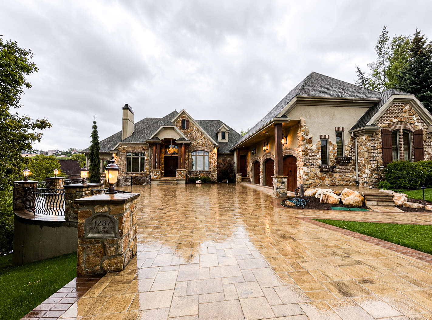 Paver Driveways in Utah Tan paver driveway leading to a luxury Utah home with stone siding and multiple garage bays, paver driveways by Empire Pavers in Utah